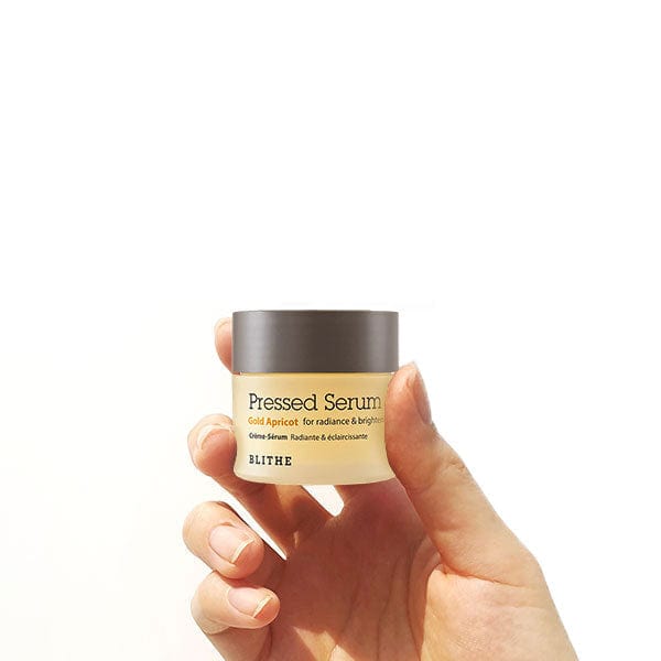 a hand holding a yellow Pressed Serum container