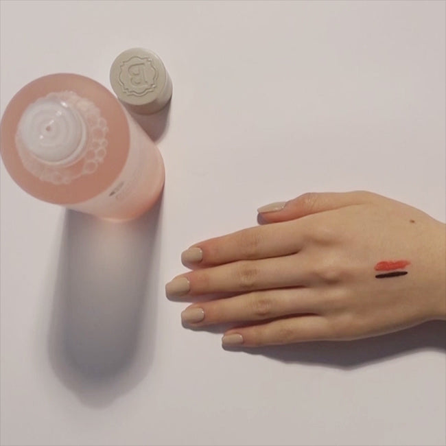 Overhead view of Blithe Anti-Polluaging Cleansing Water with Himalayan Pink Salt, demonstrating makeup removal effectiveness on hand swatches of red and black makeup.